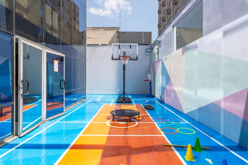 Quadra adaptada com cesta de basquete, mini trampolim e arcos coloridos