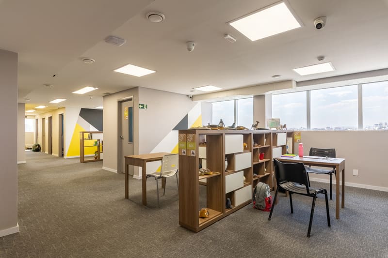 Sala clínica individualizada com mesa, prateleiras e materiais terapêuticos
