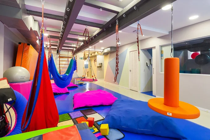 Sala de integração sensorial com balanços e equipamentos terapêuticos